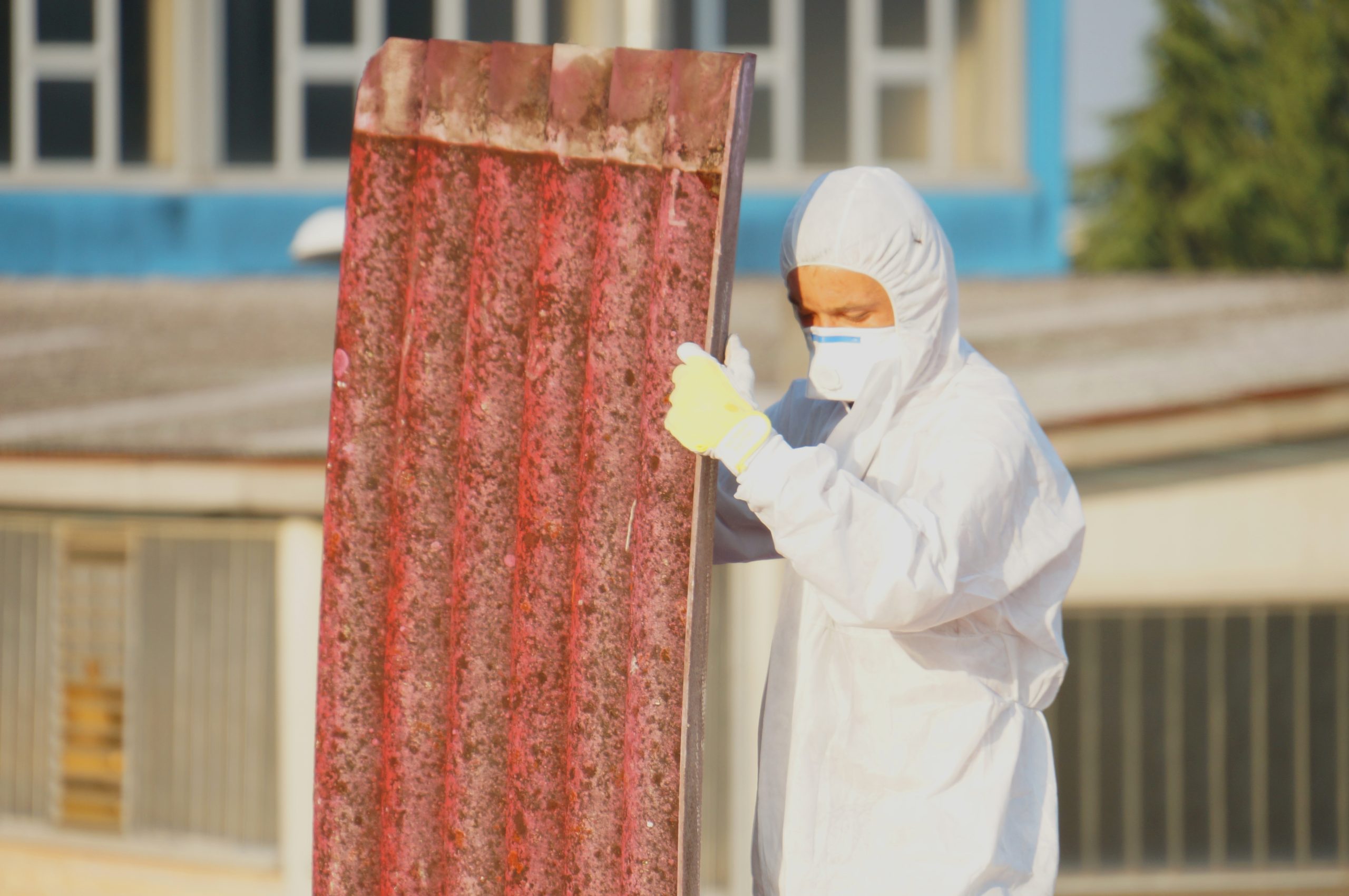 Limite di esposizione all'amianto: un lavoratore con protezioni smaltisce materiali con amianto
