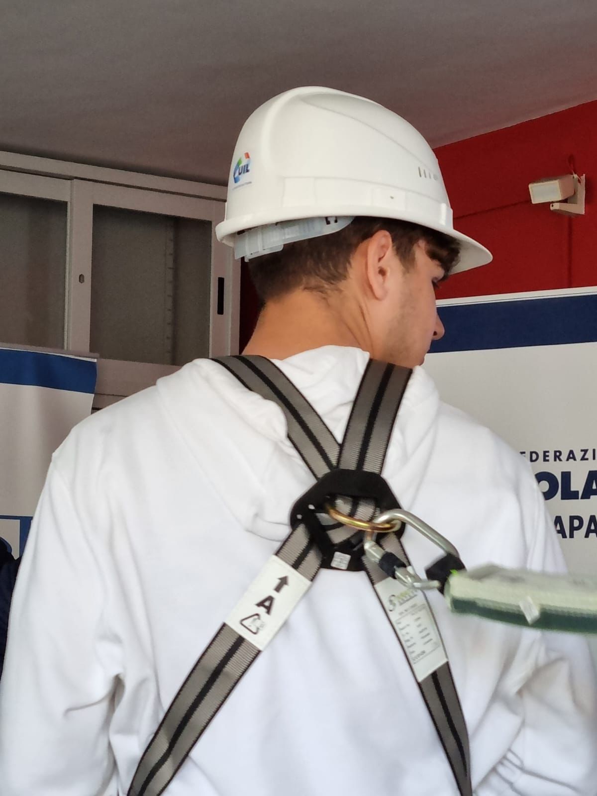 giovane ragazzo della scuola superiore indossa i dispositivi di protezione per il lavoratore edile nel corso di un incontro sulla sicurezza sul lavoro